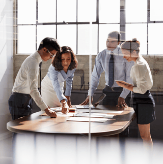 DOC_KC_PNG_Stock_4 people at work in boardroom standing around desk pointing at work-1