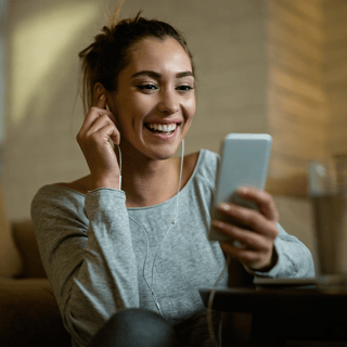 young-happy-woman-having-fun-while-using-mobile-phone-reading-text-message-her-living-room